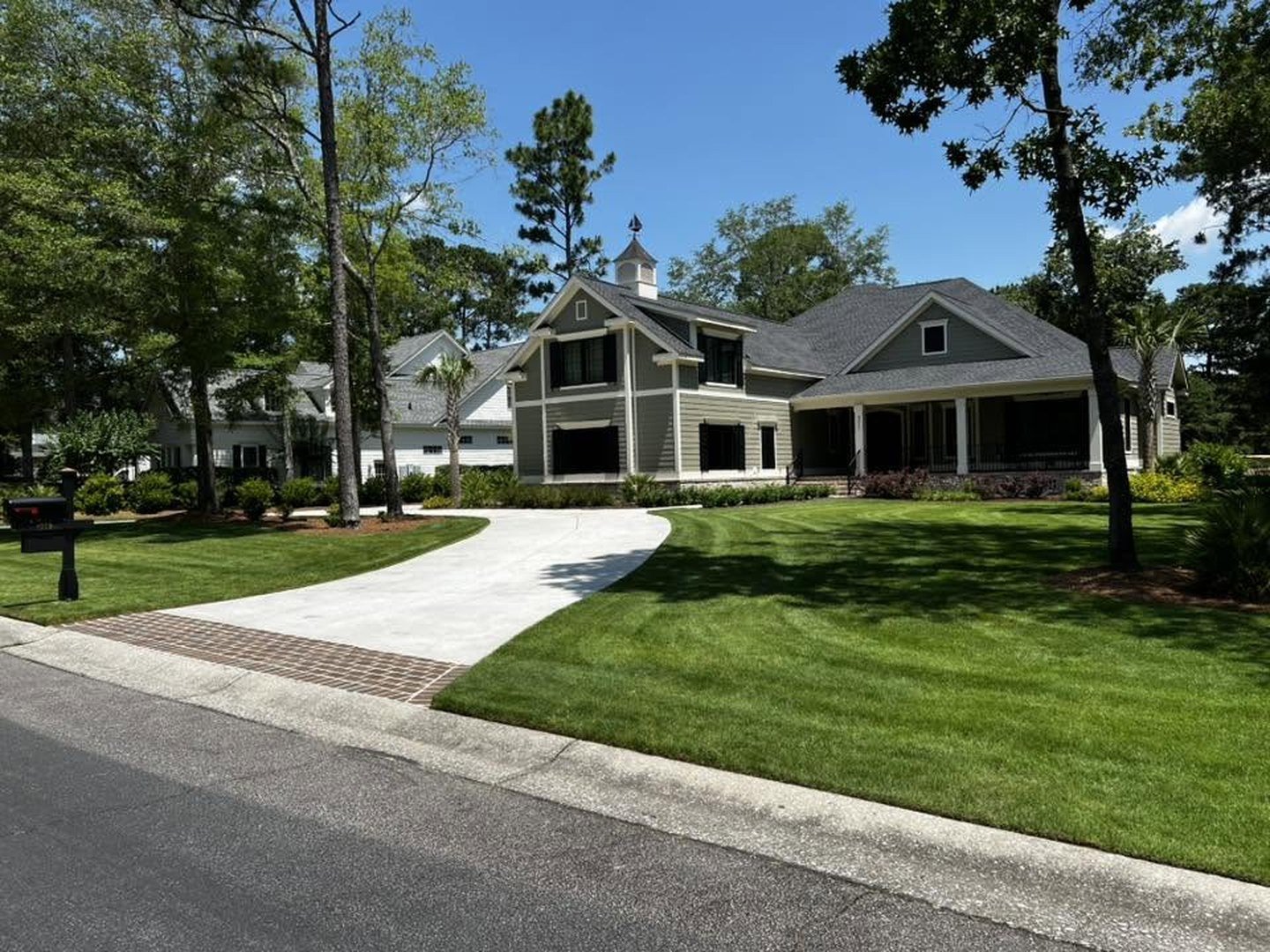 A lush, evenly green lawn in front of a large coastal-style home, maintained by Bess Irrigation